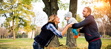 Father and mother playing with their baby outside.