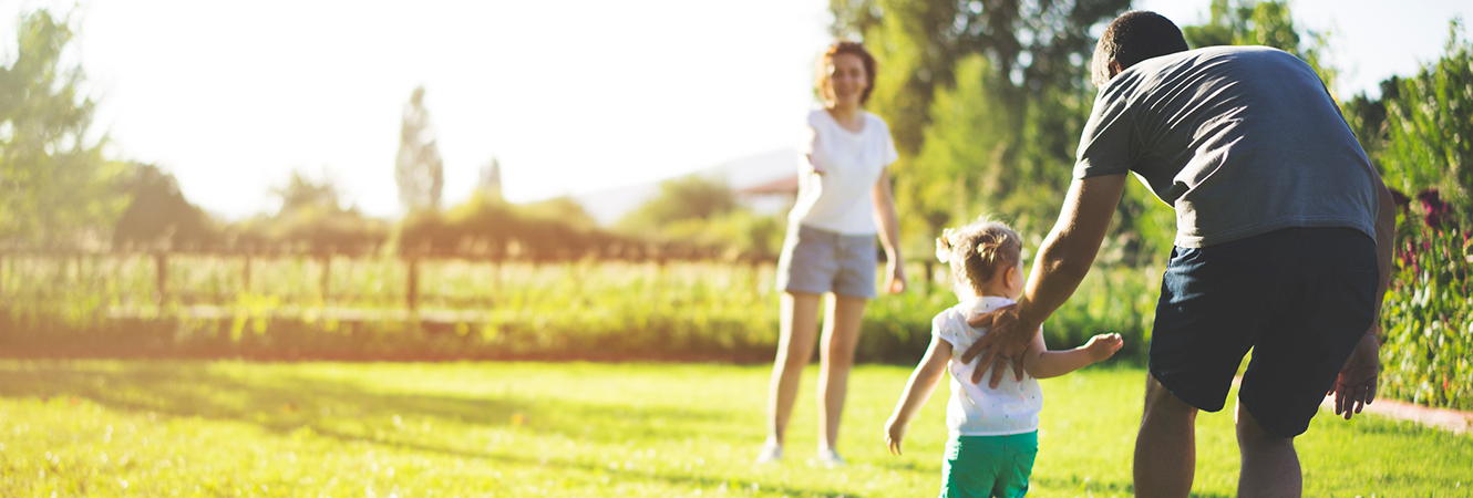 Father, mother, and daughter playing together in yard. 